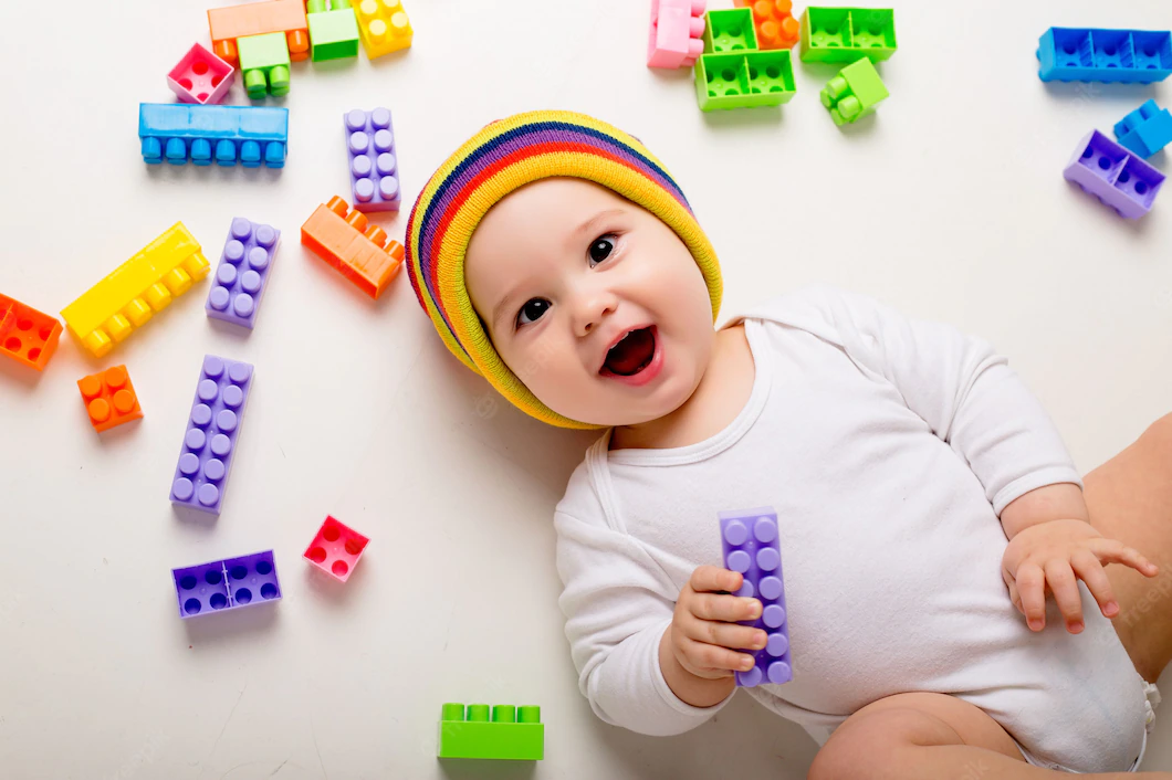 baby-boy-playing-with-multi-colored-constructor-white-wall_98296-1967